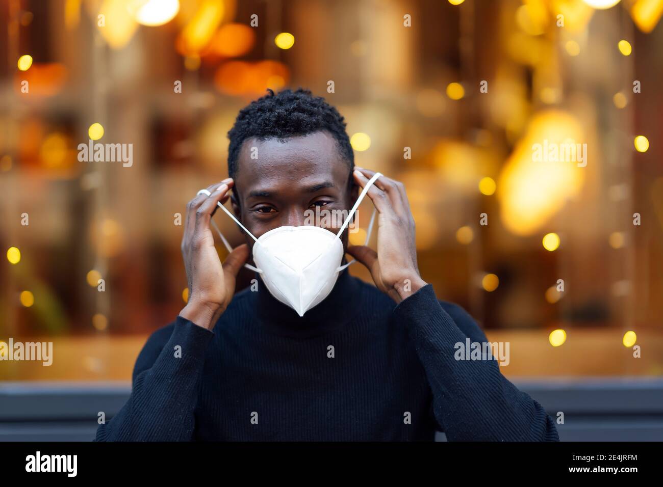 Junger Mann mit Gesichtsmaske, während er draußen während Covid-19 stand Stockfoto