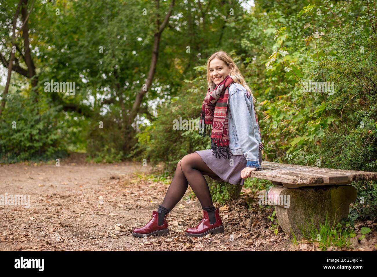 Attraktive Frau sitzt auf der Bank im herbstlichen Park Stockfoto