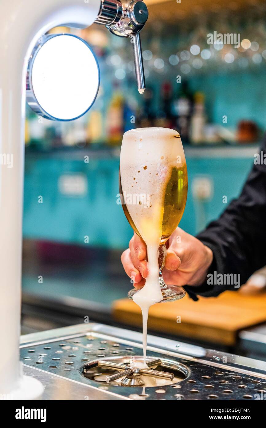 Hand des Barkeepers mit einem vollen Glas frisch gegossenem Bier Stockfoto