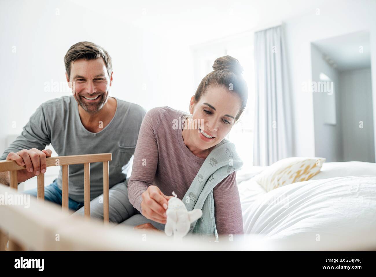 Lächelnd reifen Mann und Frau mit gefüllten Elefant Spielzeug spielen Von Kinderbett im Schlafzimmer Stockfoto