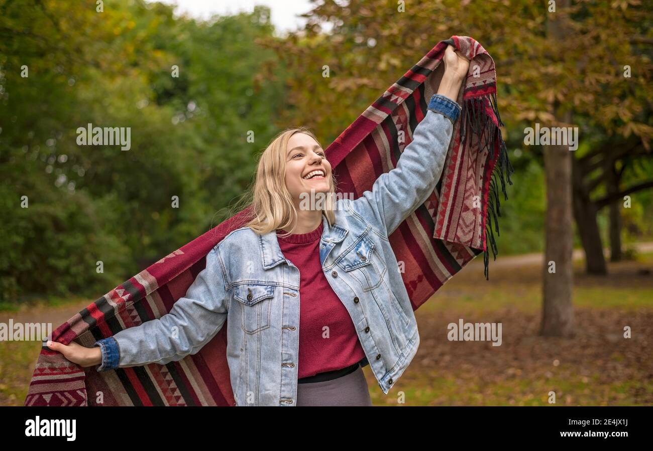 Glückliche Frau mit Schal stehen im herbstlichen Park Stockfoto