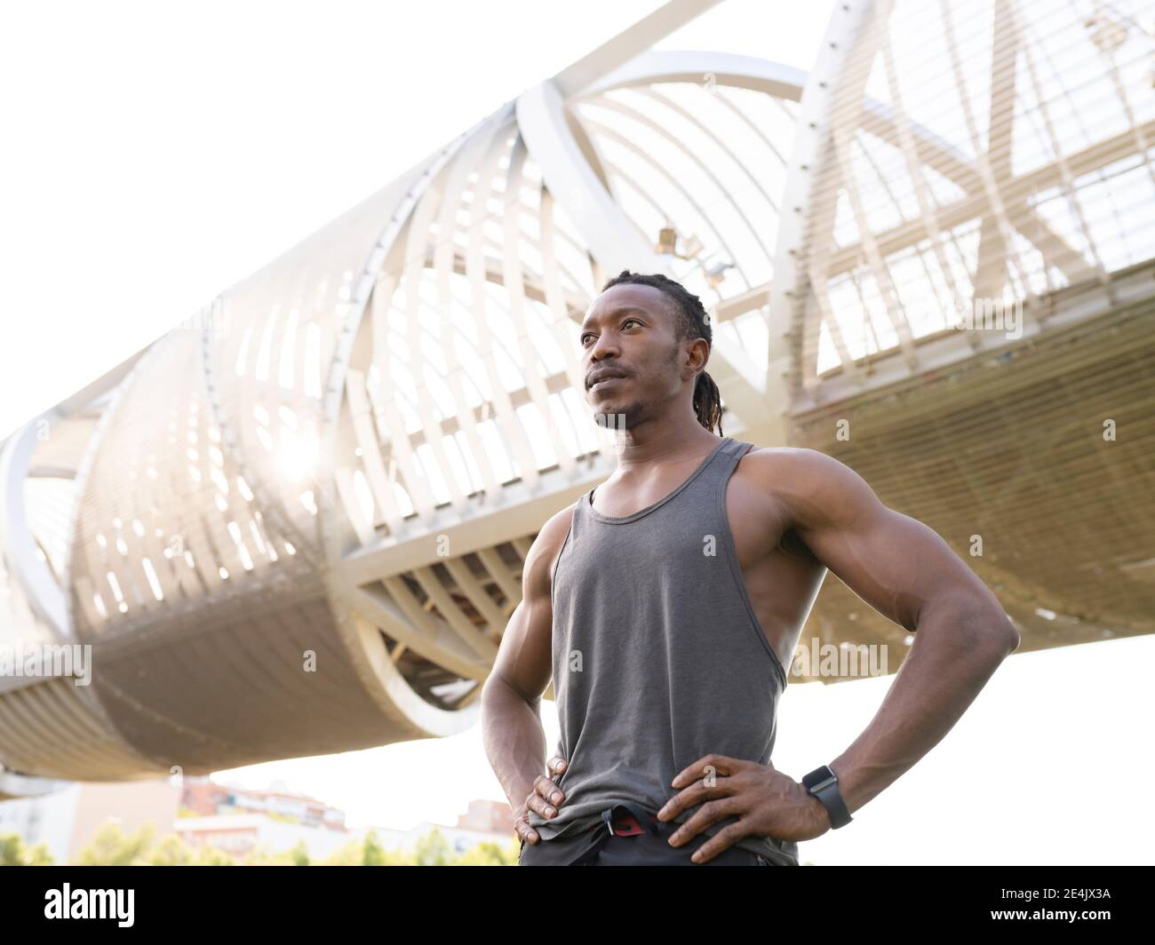Muskulöser Athlet mit Hand auf Hüfte wegschauen während Gegen den Gehweg stehen Stockfoto