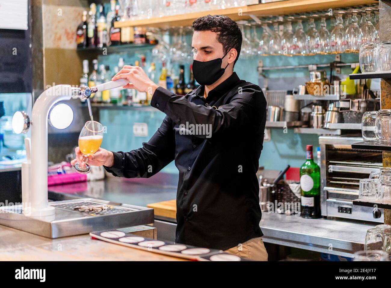 Porträt des Barkeepers mit Schutzmaske Bier serviert Stockfoto