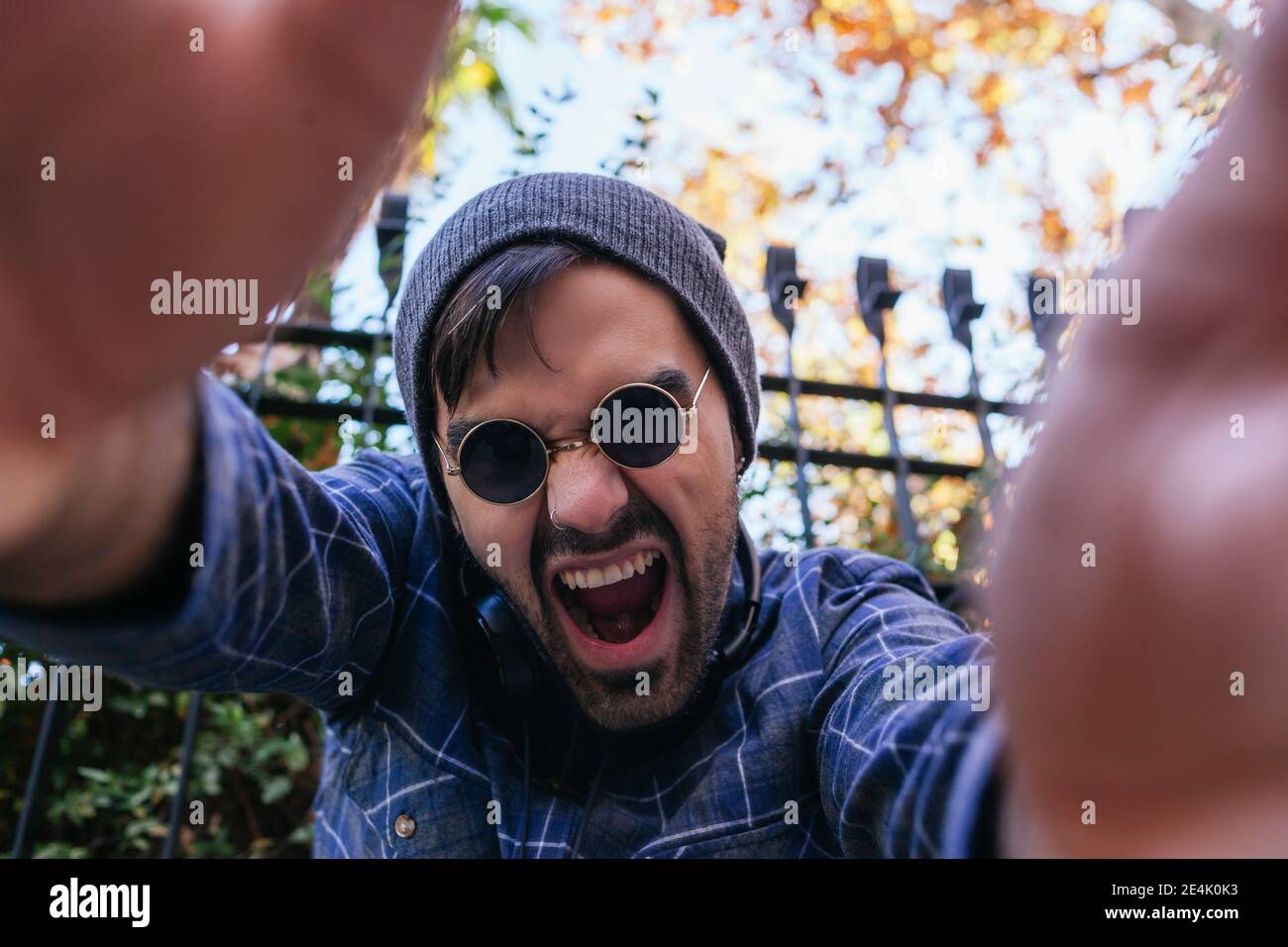Junger Mann mit offenem Mund gestikuliert im öffentlichen Park Stockfoto