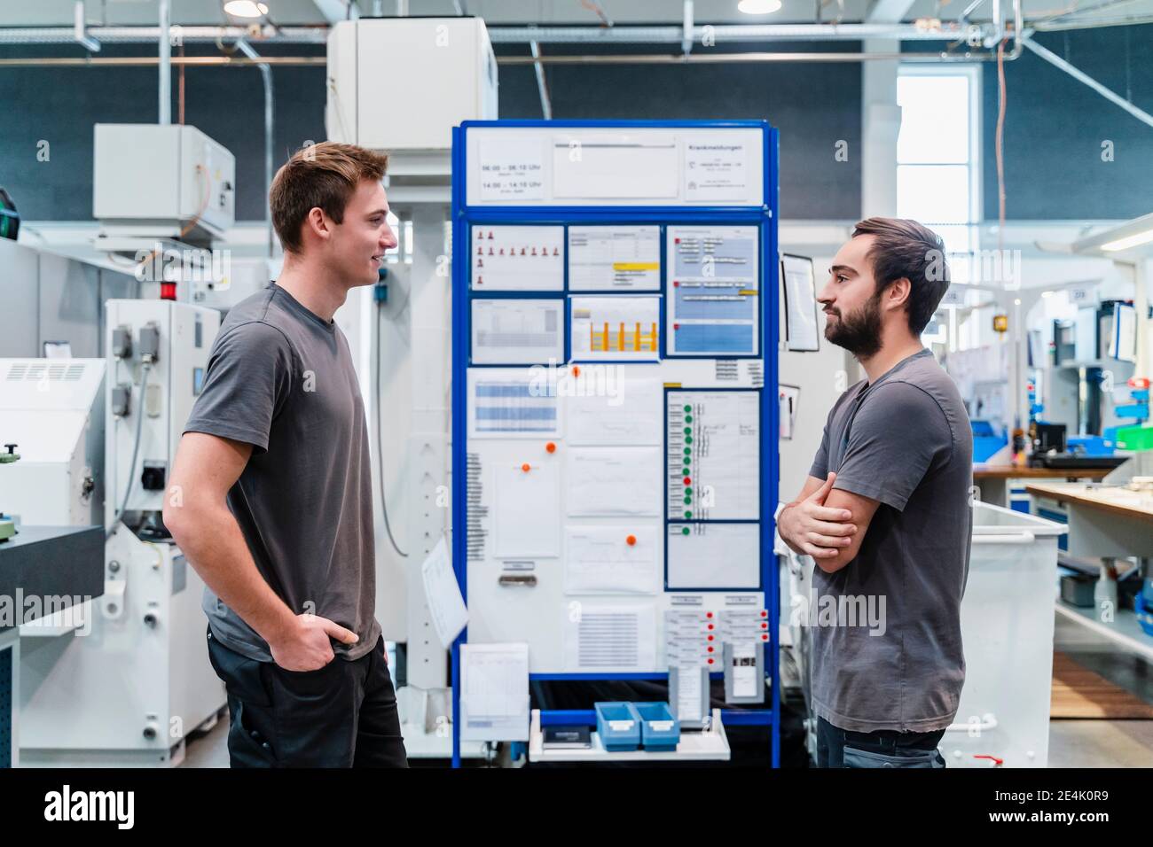 Wartungsarbeiter, die einander beim Stehen in der Fabrik betrachten Stockfoto