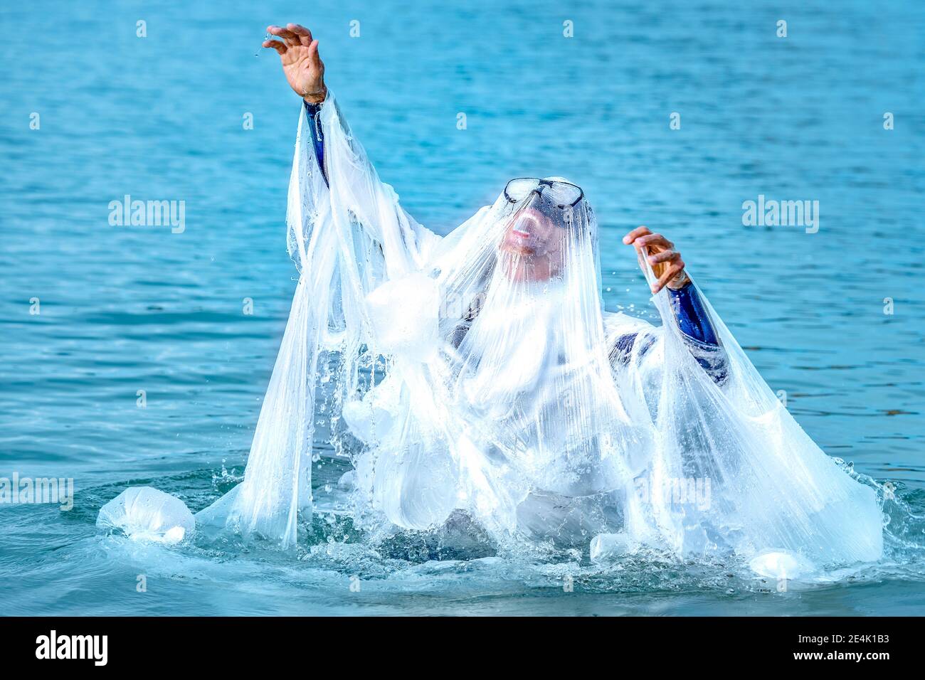 Reifer Mann bedeckt mit Plastik schreien, während Schwimmen im Meer Stockfoto