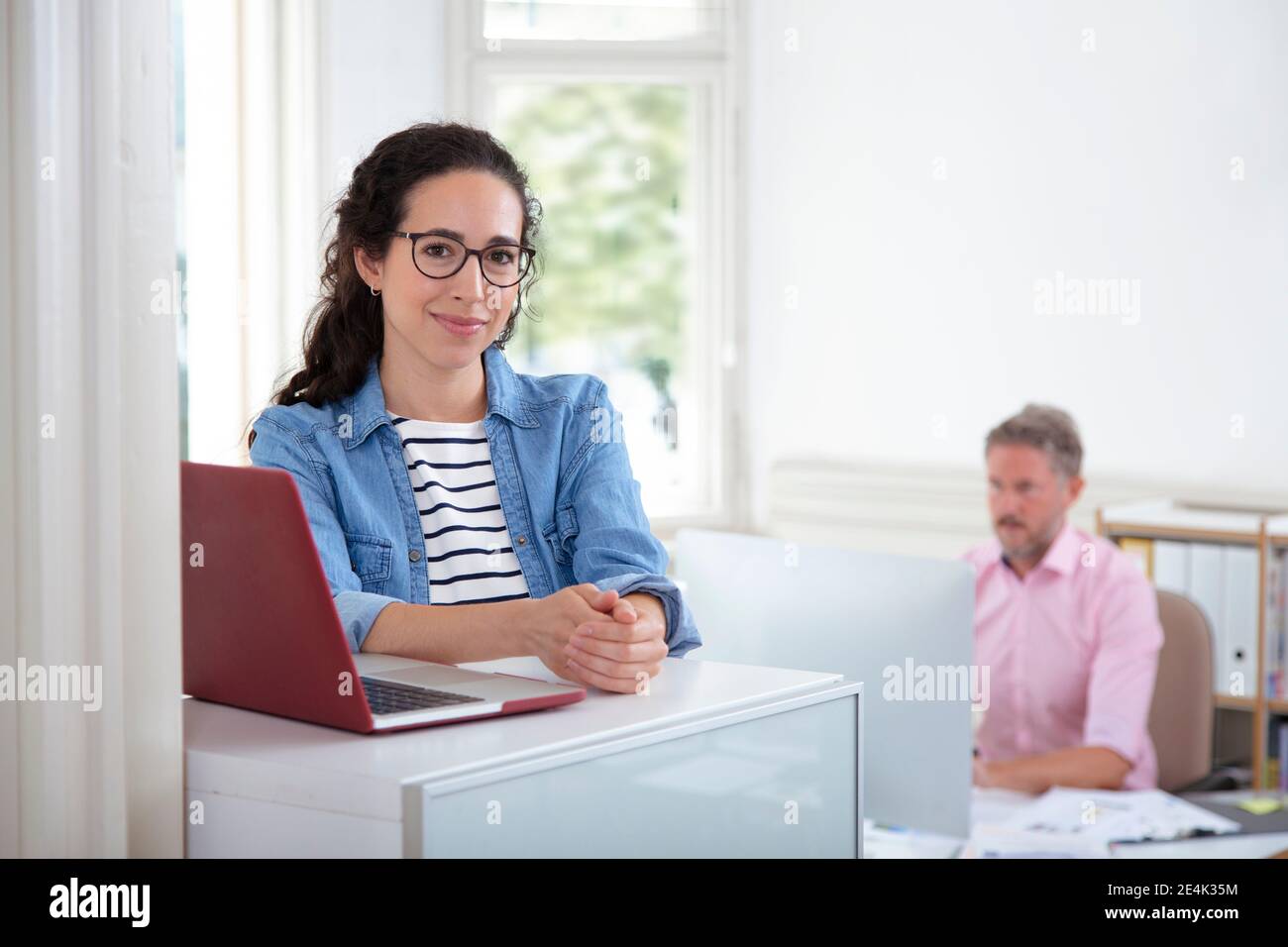 Lächelnd weibliche Profi mit männlichen Kollegen im Hintergrund Stockfoto Lächelnd weibliche Profi mit männlichen Kollegen im Hintergrund Stockfoto