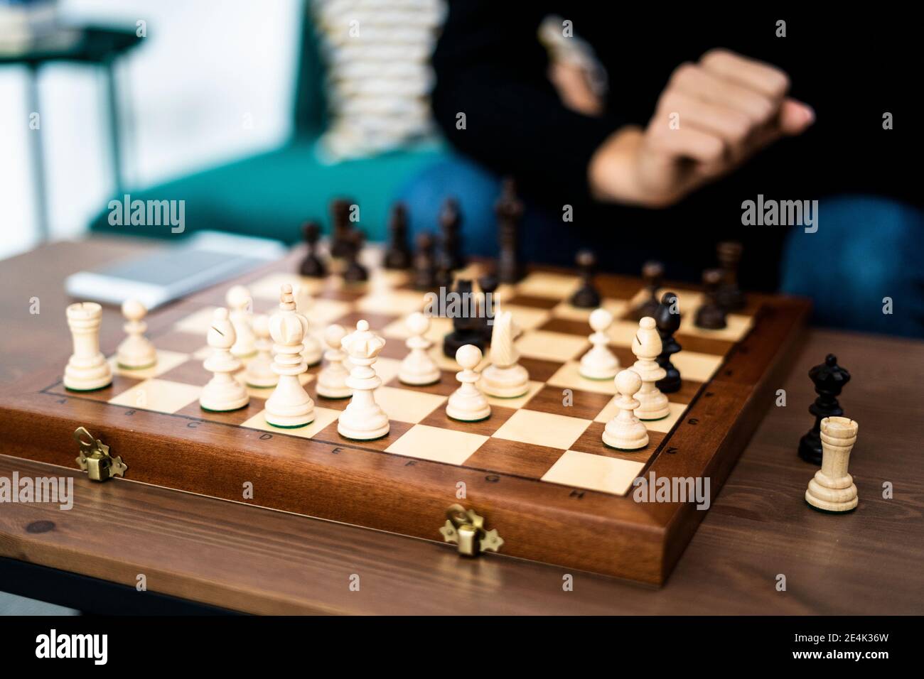 Junge Frau spielt Schach im Wohnzimmer Stockfoto
