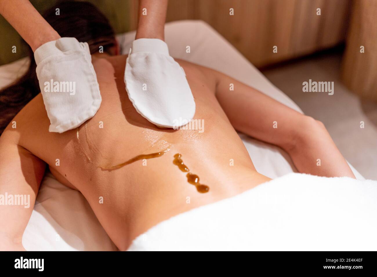 Weibliche Therapeutin massiert den Rücken der Frau mit Öl im Beauty Spa Stockfoto