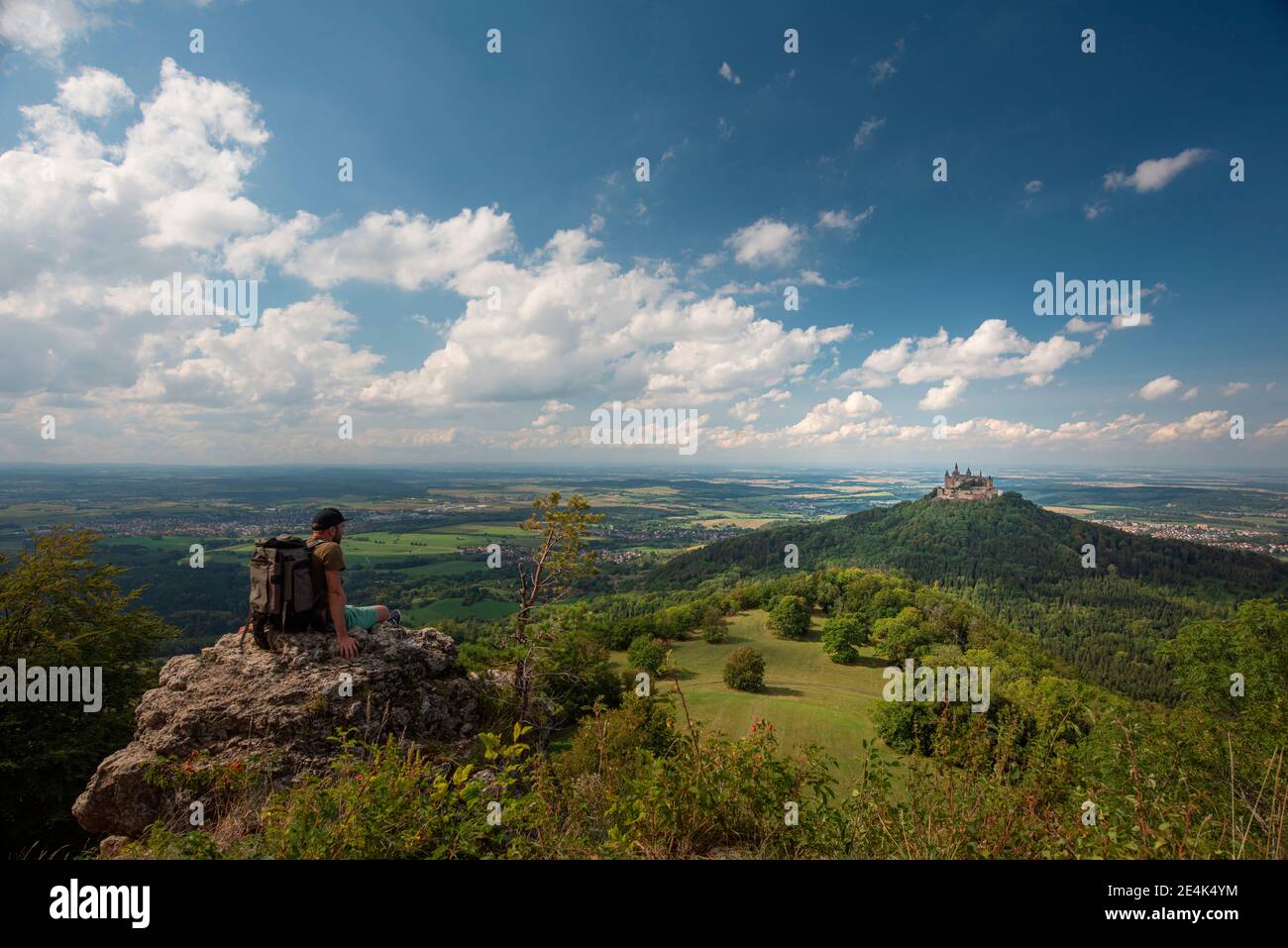 Wanderer mit Blick auf die Burg Hohenzollern, während er auf dem Berg auf der Schwäbischen Alb sitzt Stockfoto