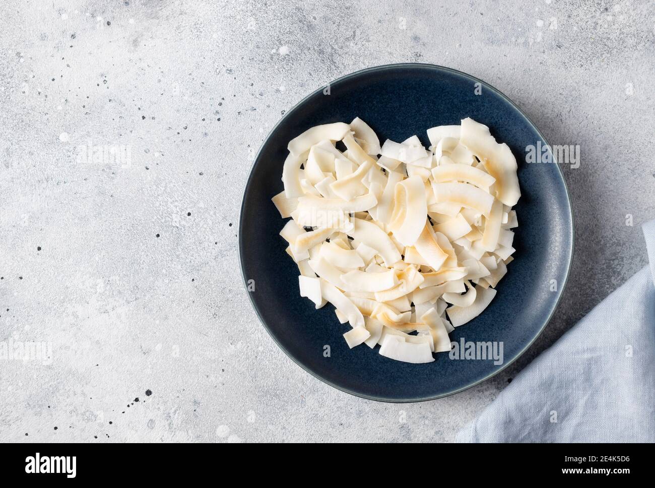 Herz aus Kokosnuss-Chips, in blauer Platte. Gesunde Ernährung Konzept Stockfoto