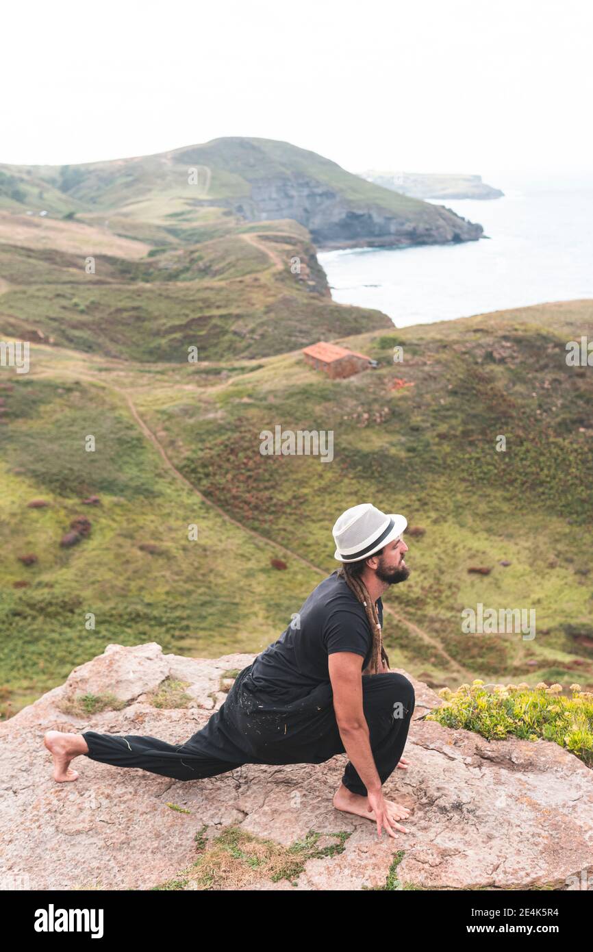 Junger Mann beim Yoga in der Natur auf dem Berg in Santander, Spanien Stockfoto