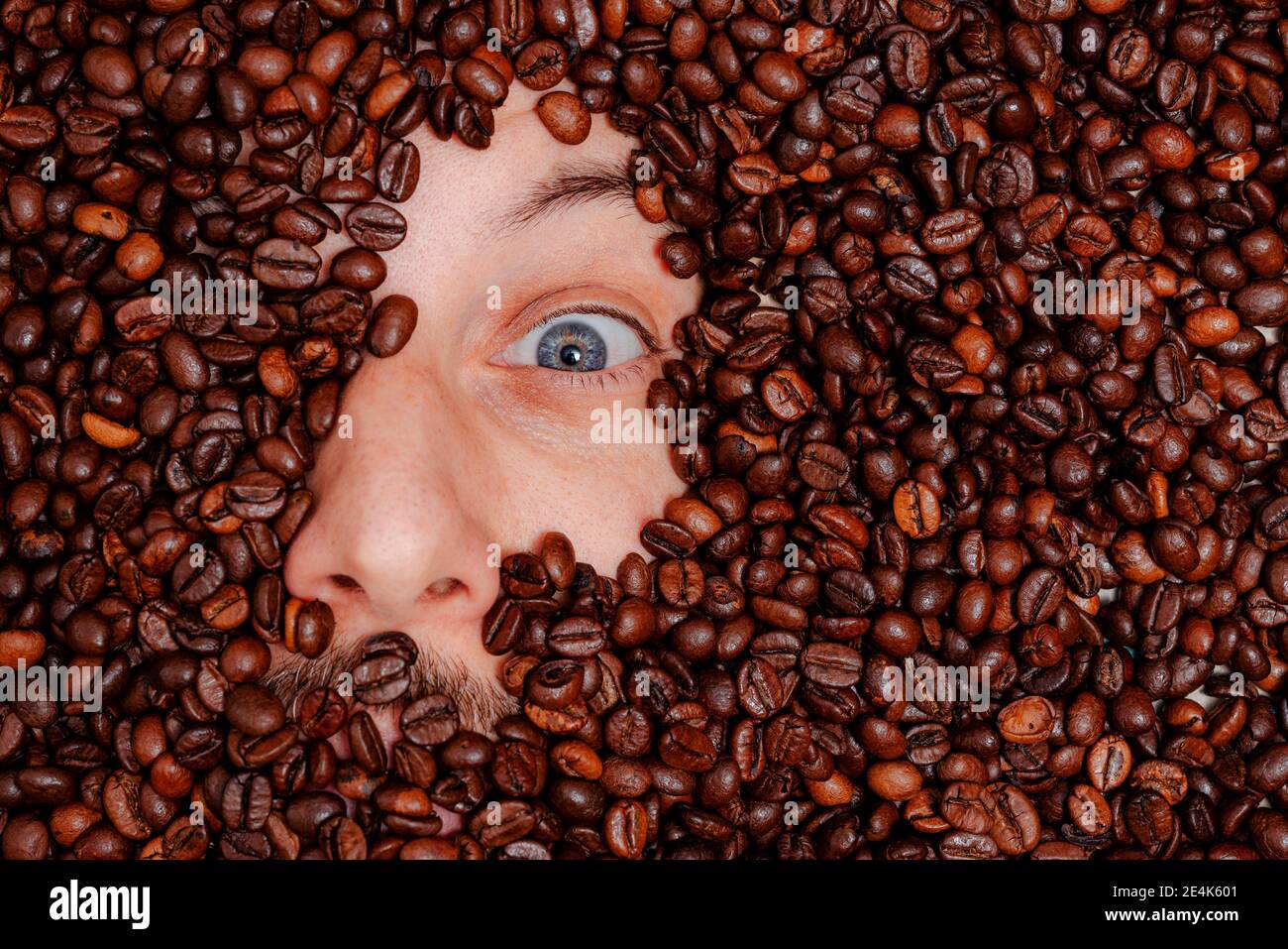 Menschliches Gesicht in gerösteten Kaffeebohnen vergraben Stockfoto