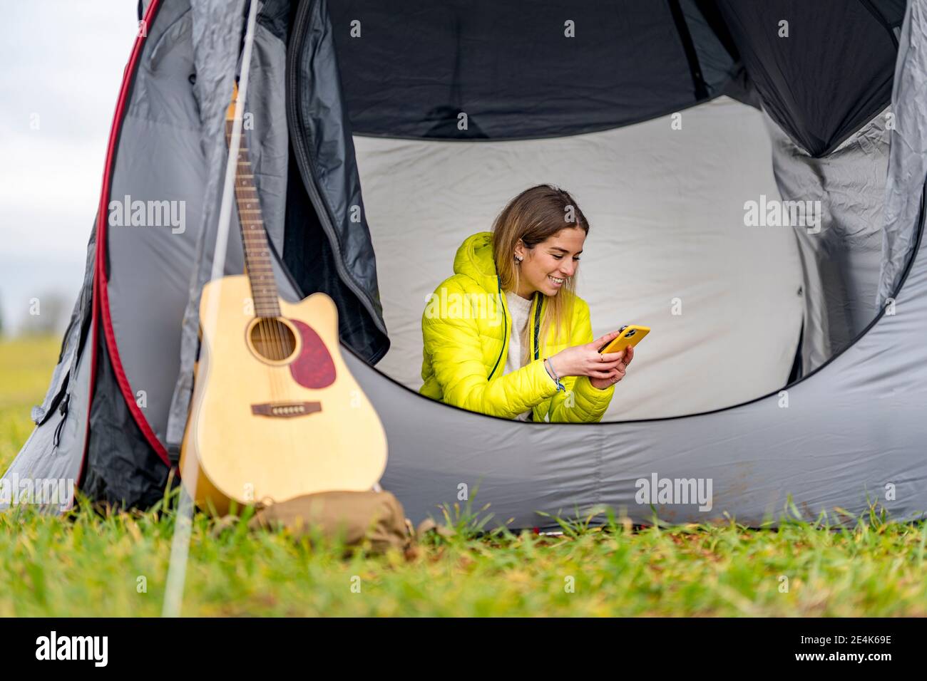 Junge Frau mit Smartphone im Zelt Stockfoto