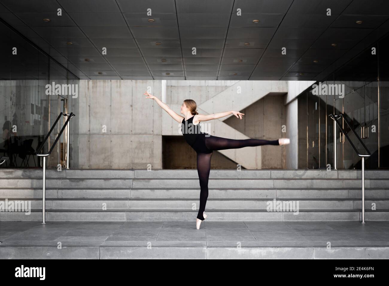 Ballerina in schwarzem Trikot in modernem Betongebäude Stockfoto