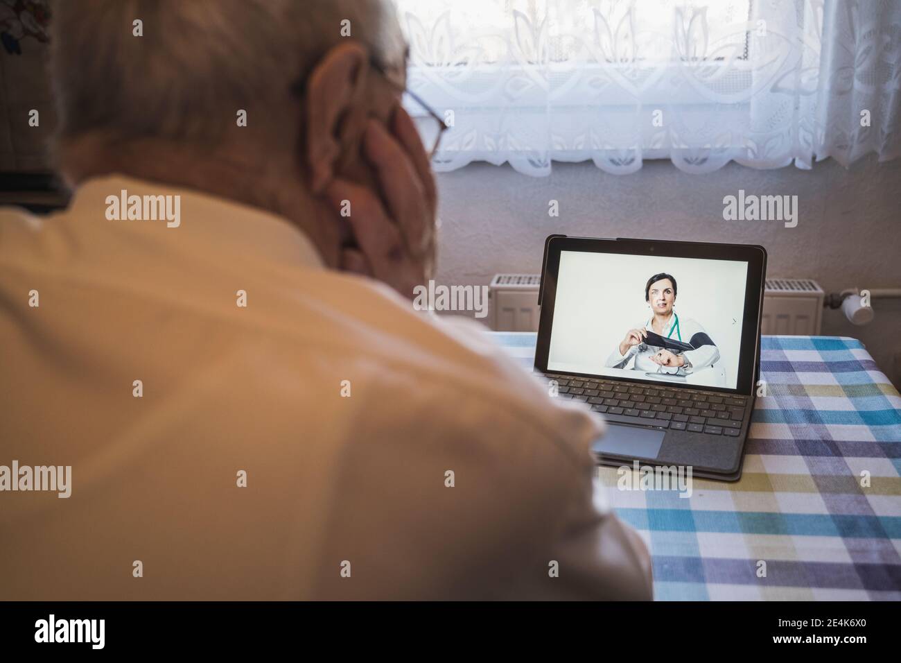 Ärztin zeigt männlichen Patienten, wie man den Blutdruck überprüft Videoanruf über Laptop zu Hause Stockfoto