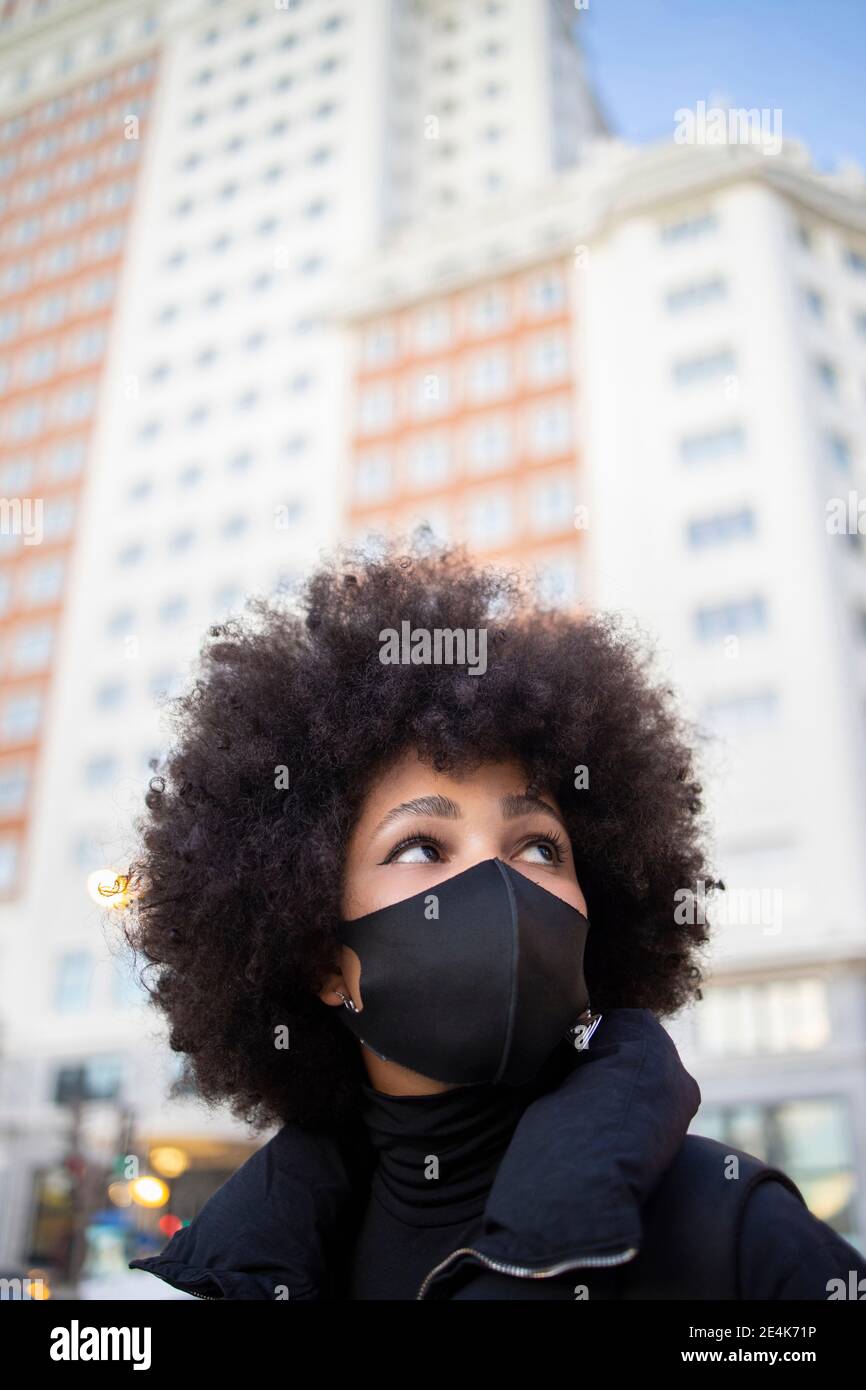 Afro junge Frau hält Einweg-Kaffeetasse, während sie ein Taxi auf der Stadtstraße anhagelt Stockfoto