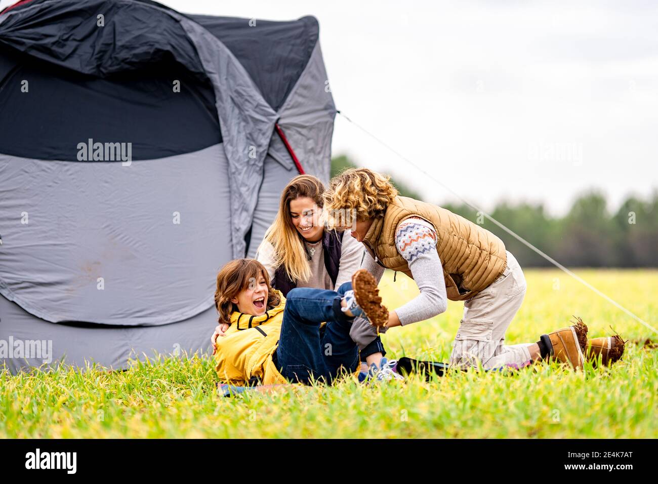 Drei Geschwister spielen auf Gras vor dem Zelt Stockfoto