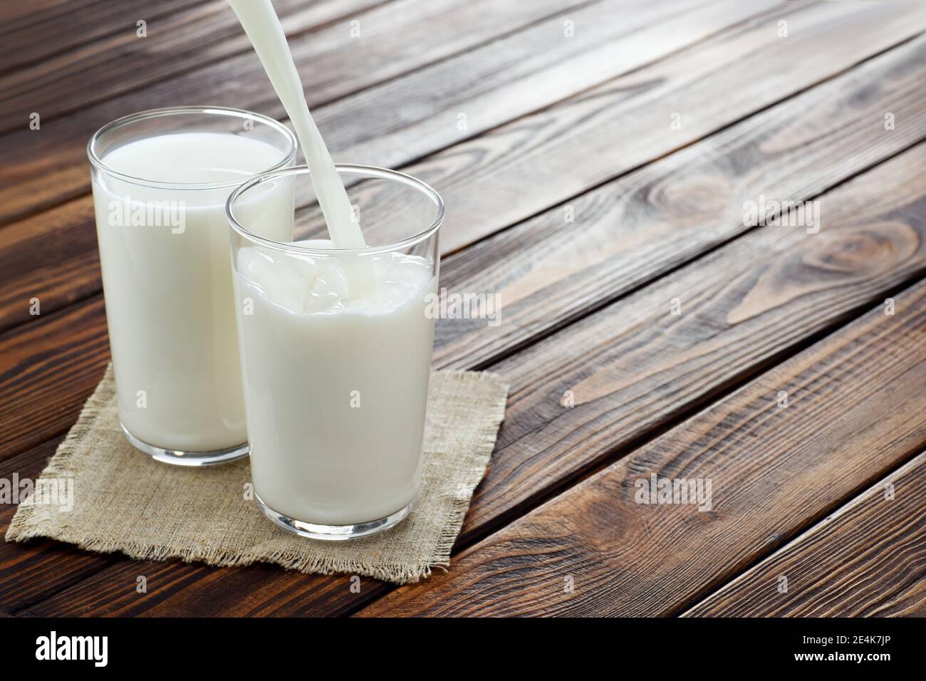 Milch in Glas gießen Stockfoto