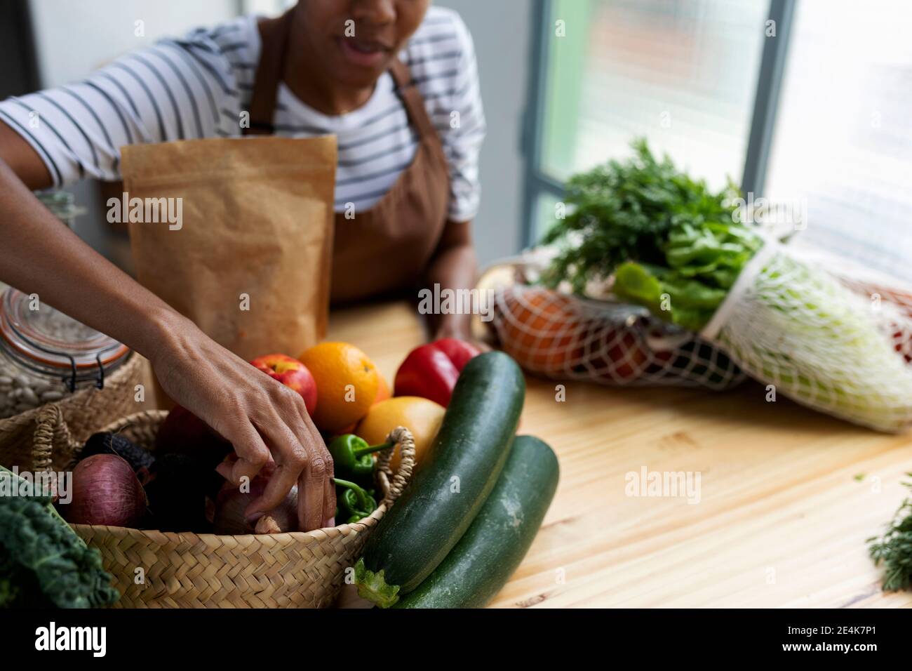Frau mit Schürze in der Küche, Auspacken frisch gekauftes Bio-Obst und Gemüse Stockfoto