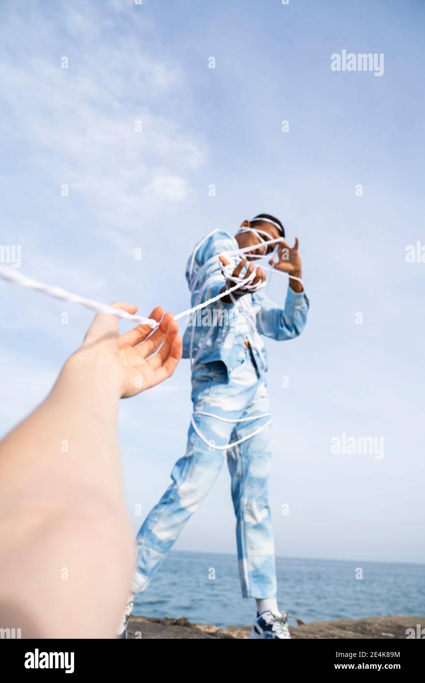 Männer ziehen, während sie sich vom Seil gegen den Himmel befreien Stockfoto