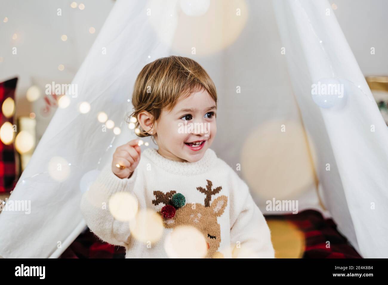 Nettes Baby Mädchen schaut weg, während sie gegen Zelt an steht Zuhause während Weihnachten Stockfoto