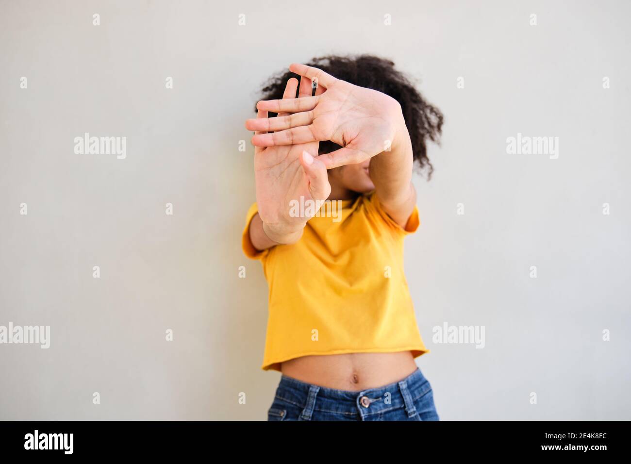 Frau mit Stop-Geste, während sie gegen die weiße Wand steht Stockfoto
