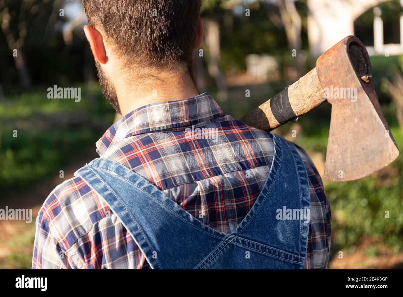 Mann in Overalls mit Axt an sonnigen Tagen Stockfoto