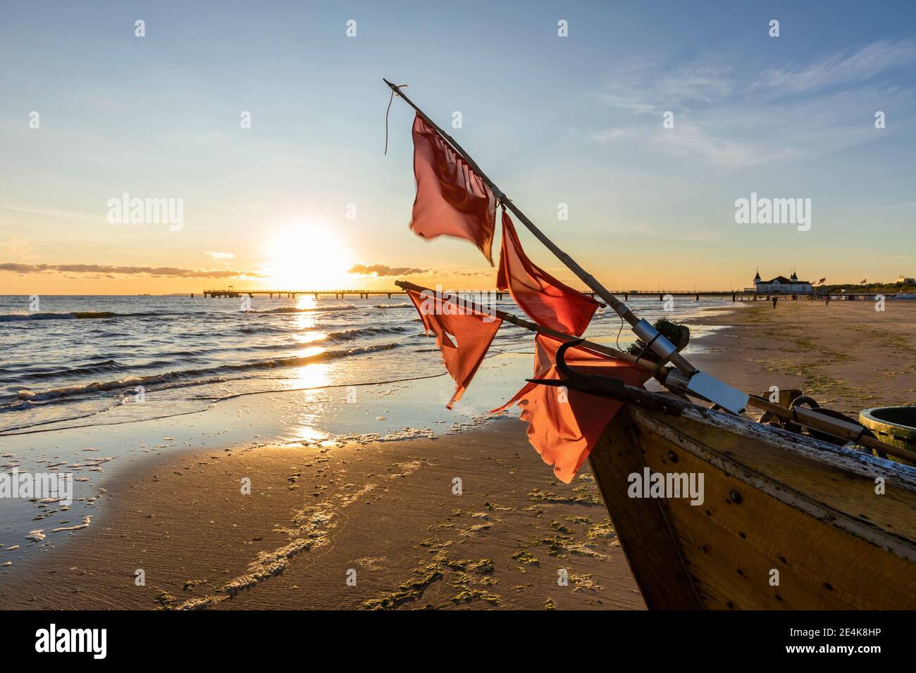 Deutschland, Mecklenburg-Vorpommern, Ahlbeck, Rote Flaggen auf Fischerboot am sandigen Küstenstrand bei Sonnenaufgang Stockfoto