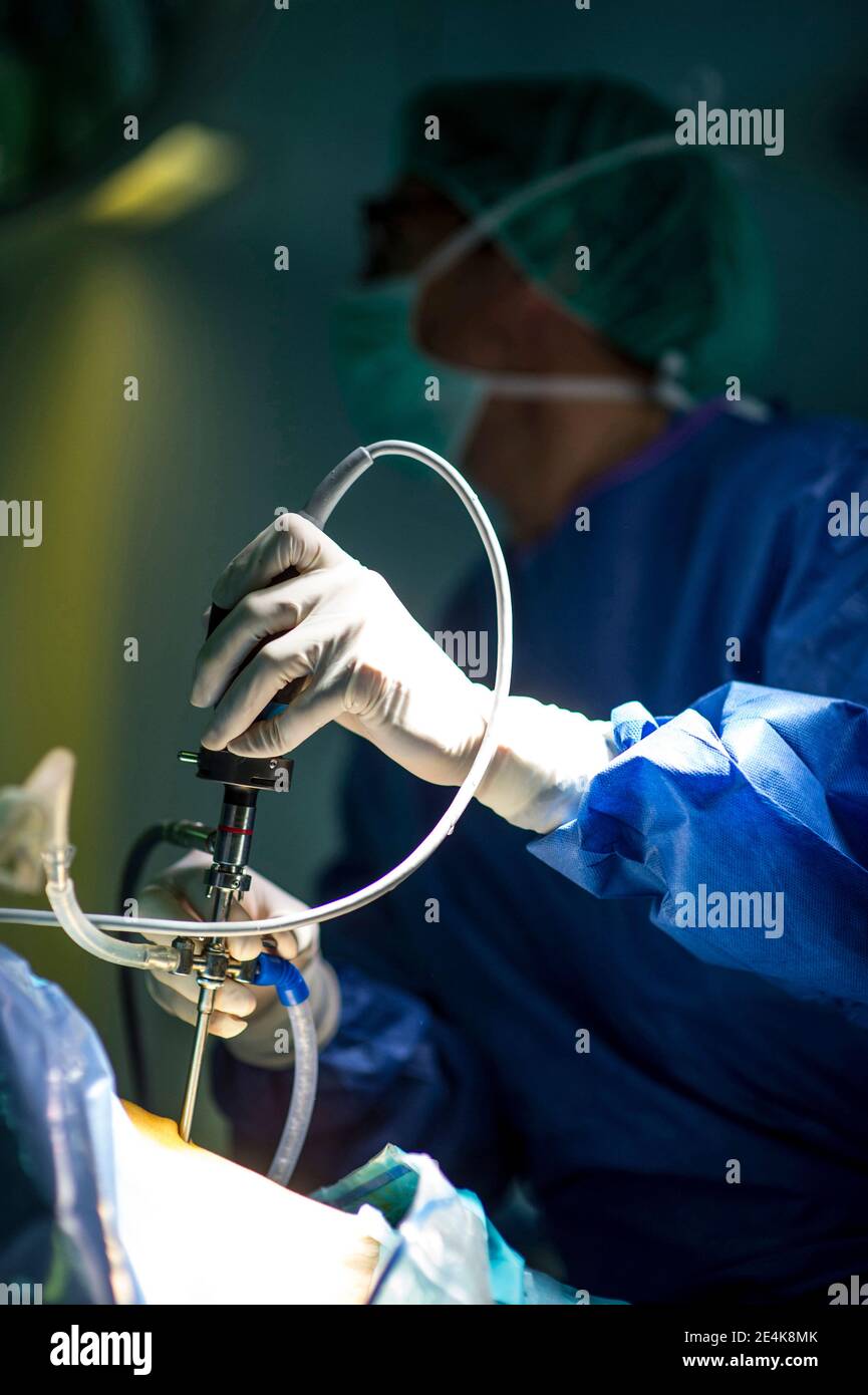 Männlicher Chirurg mit Mitarbeiter, der auf der Intensivstation im Krankenhaus operiert Stockfoto