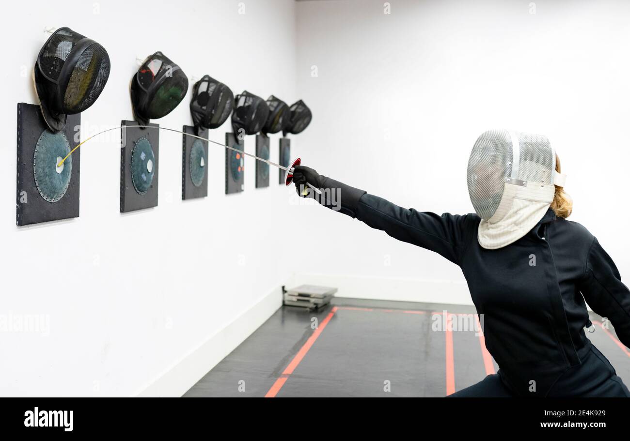 Frau trifft Ziel mit Fechtschwert im Fitnessstudio Stockfoto