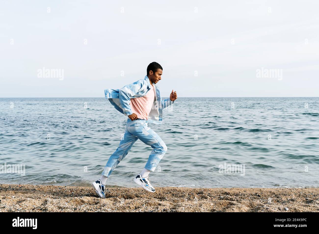 Mann trägt Wolken Denim Anzug läuft auf dem Weg gegen das Meer Stockfoto