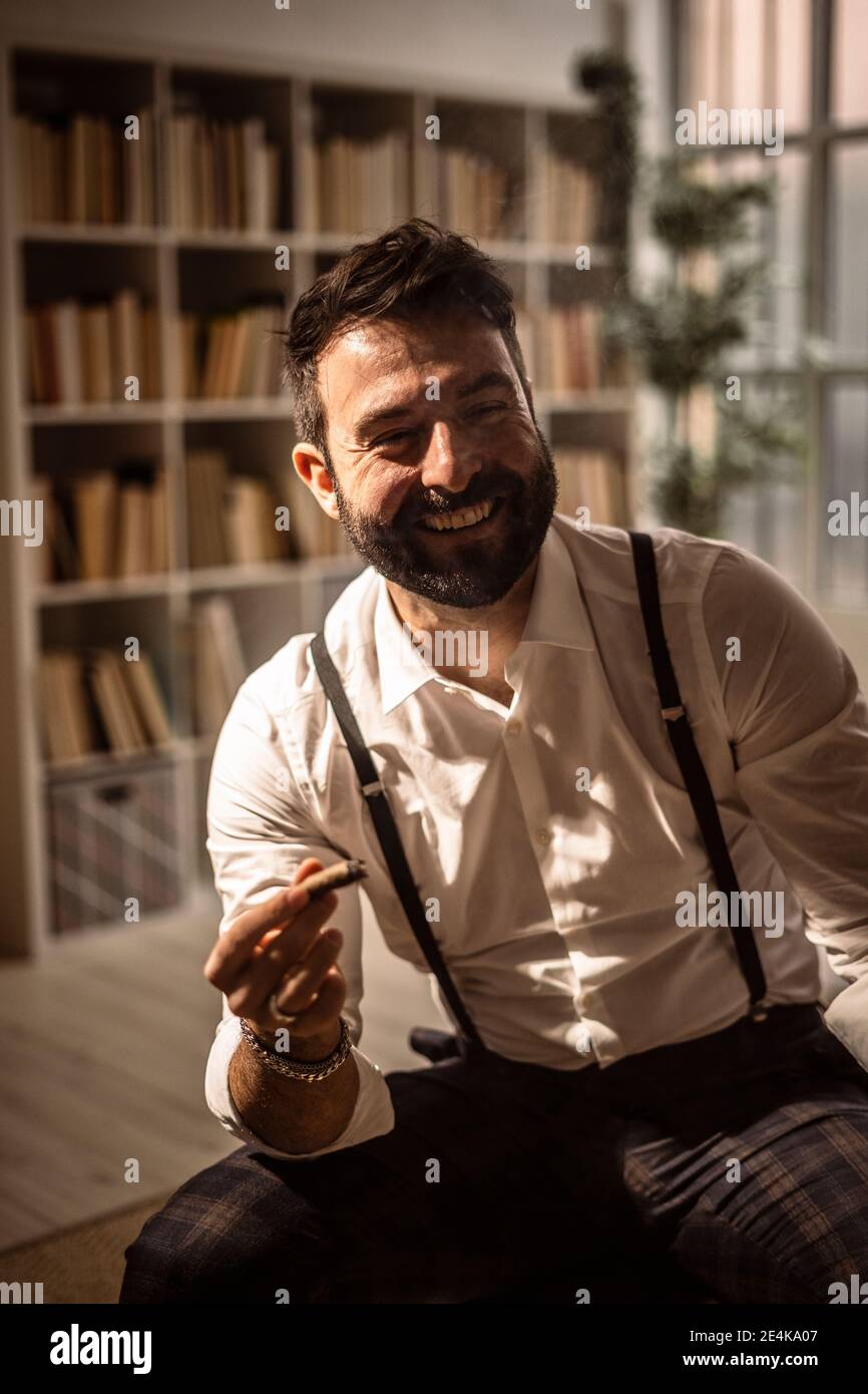 Porträt eines bärtigen Mannes, der beim Zigarren lacht Stockfoto