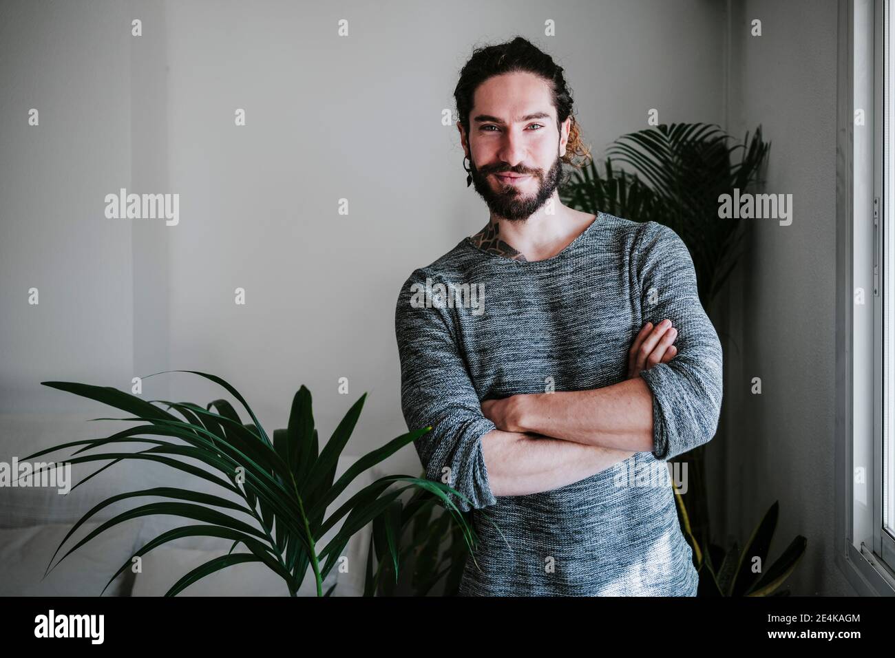 Junger Mann, der zu Hause mit gekreuzten Armen steht Stockfoto