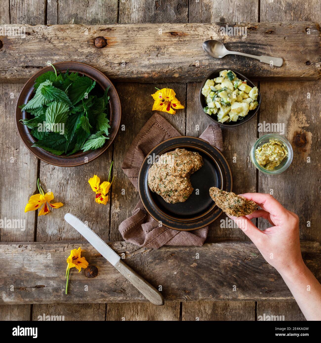 Kartoffelsalat, frische Brennnessel, Kräuterbutter und gelbe Blütenköpfe Stockfoto