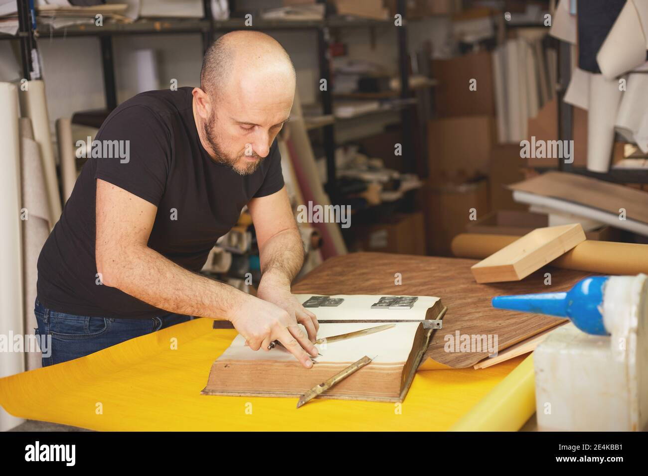 Buchbinder stellt altes Buch in Handwerkswerkstatt wieder her Stockfoto