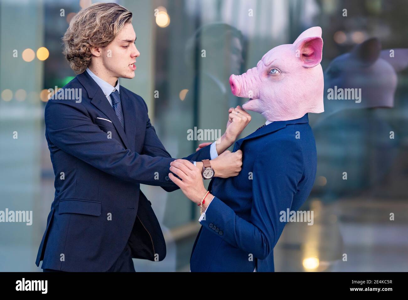 Männlich professionelle Stanzen Kollegen in Schwein Maske während stehen Glaswand Stockfoto