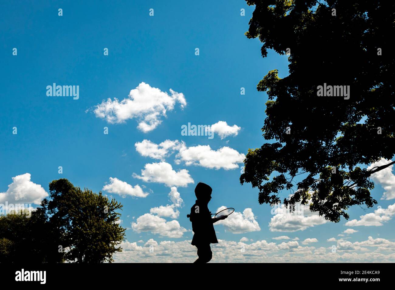 Silhouette Junge mit Badminton Schläger steht gegen blauen Himmel Stockfoto