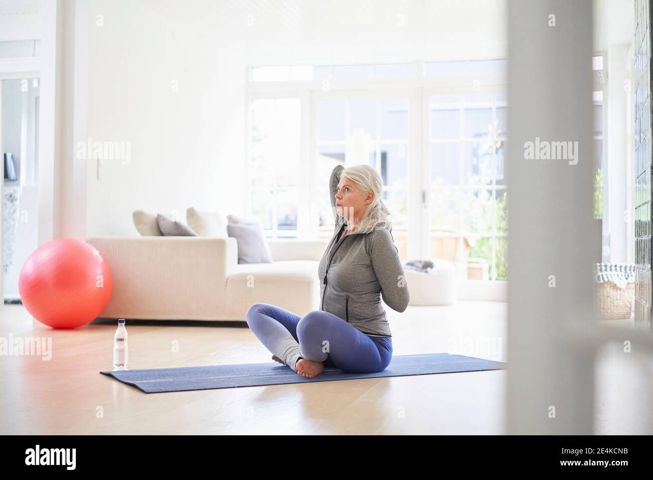 Ältere Frau mit den Händen hinter dem Rücken im Wohnzimmer trainieren Stockfoto