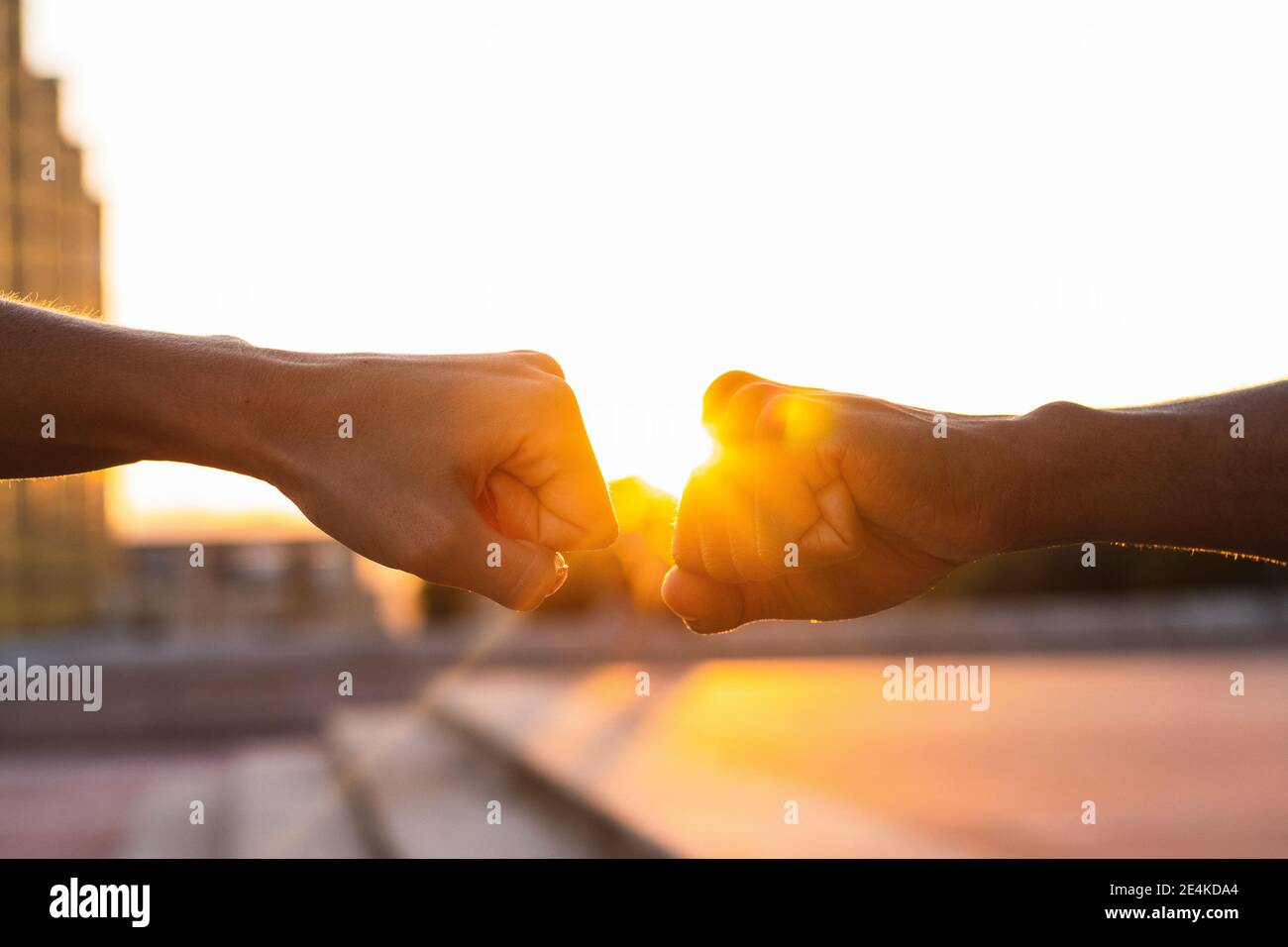 Hände von Freunden geben Faust Beule gegeneinander Klarer Himmel bei Sonnenuntergang Stockfoto