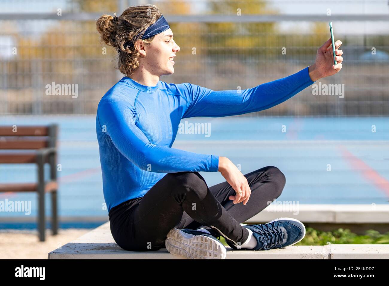 Lächelnder Sportler nimmt Selfie im öffentlichen Park an sonnigen Tag Stockfoto