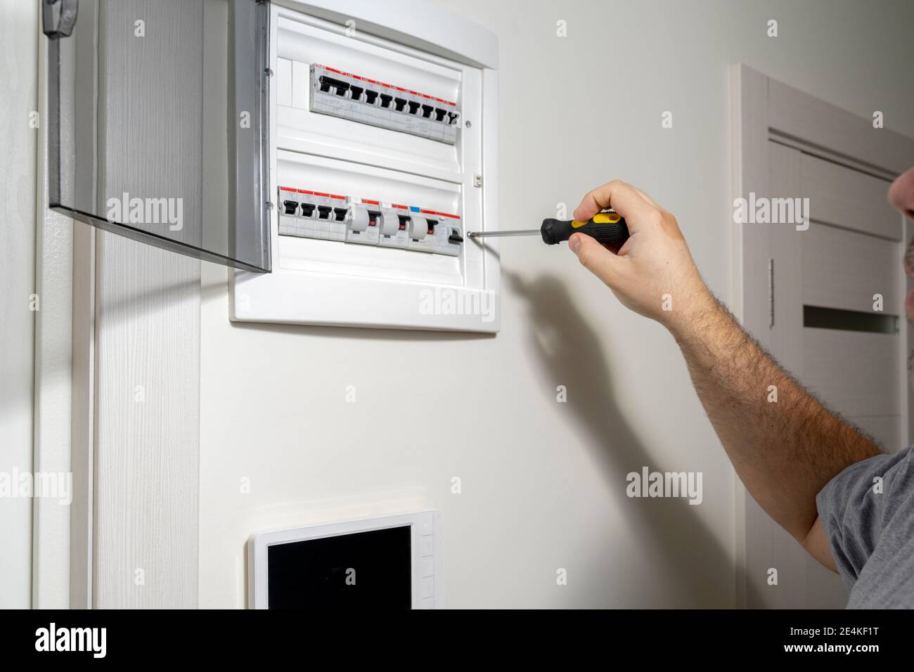 Nahaufnahme eines Elektrotechnikers, der in einer Elektroschalttafel im Wohngebäude arbeitet. Überprüfen Sie die Parameter des Kraftwerks. Stockfoto