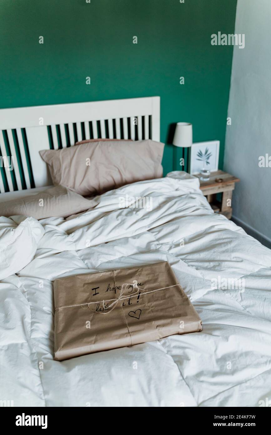 Geschenk eingewickelt in braunem Papier auf dem Bett zu Hause Stockfoto