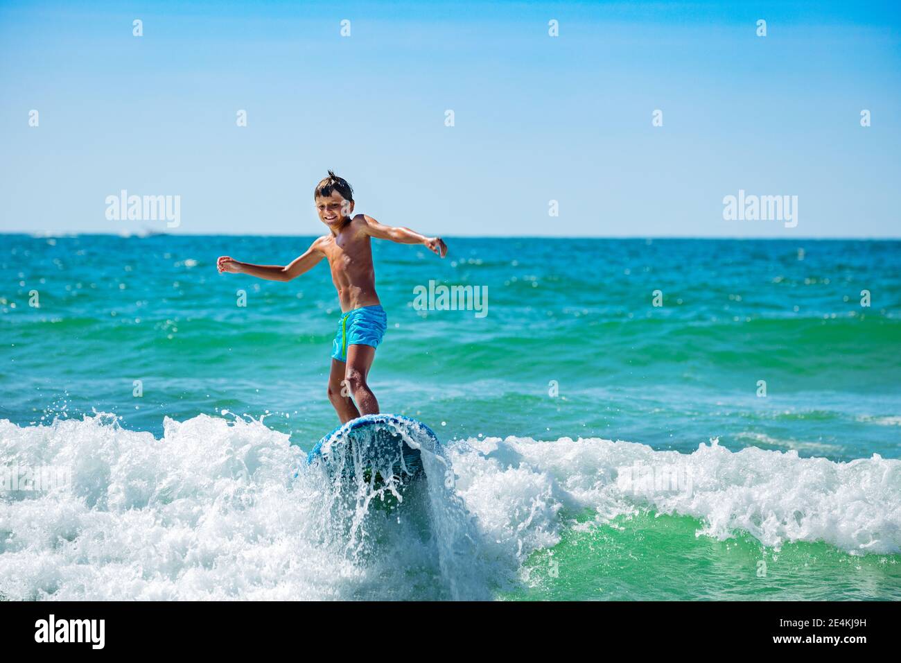 Coole kleine Surfboarder, junge 10 Jahre alten Jungen reiten Wellen in Action-Shooting Stockfoto