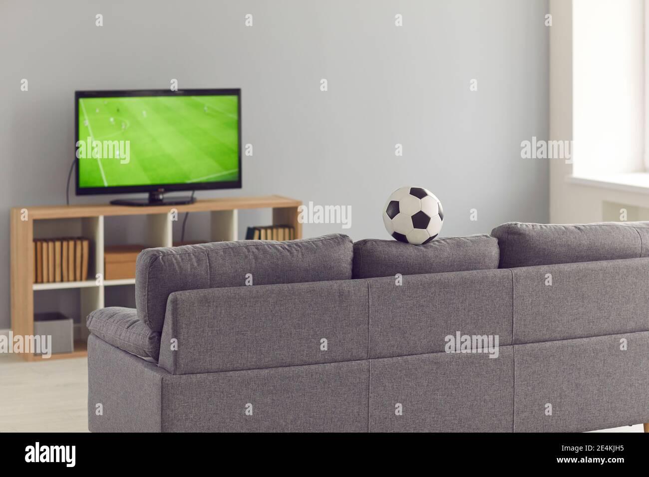 Modernes Wohnzimmer mit grauer Couch und Fernseher Mit einem Fußballspiel Stockfoto