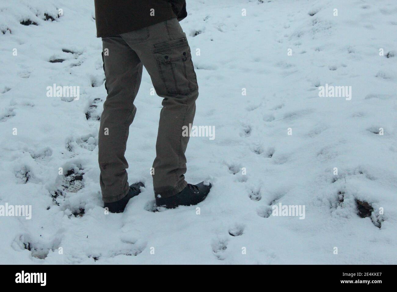Ein Foto der unteren Hälfte eines Mannes in Outdoor-Kleidung stand im Neuschnee Stockfoto