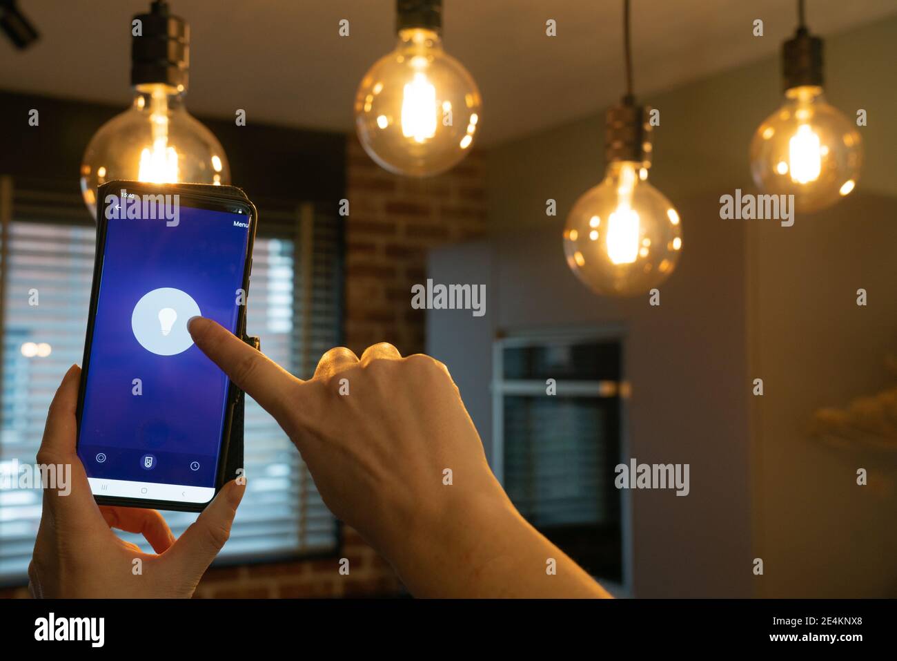 Intelligentes Zuhause. Handsteuerung Smart-Lampen mit App auf dem Telefon. Elektrisches Konzept. Stockfoto