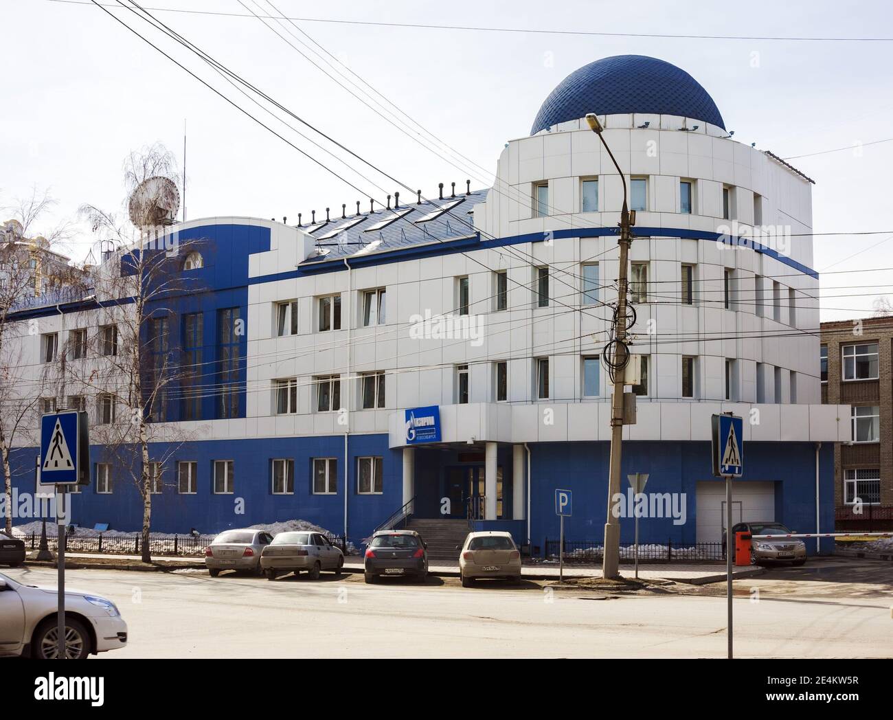 Service-Gebäude der Öl-und Gasgesellschaft Gazprom Mezhregiongaz Nowosibirsk mit geparkten Autos in der Nähe an einem Frühlingstag. Stockfoto
