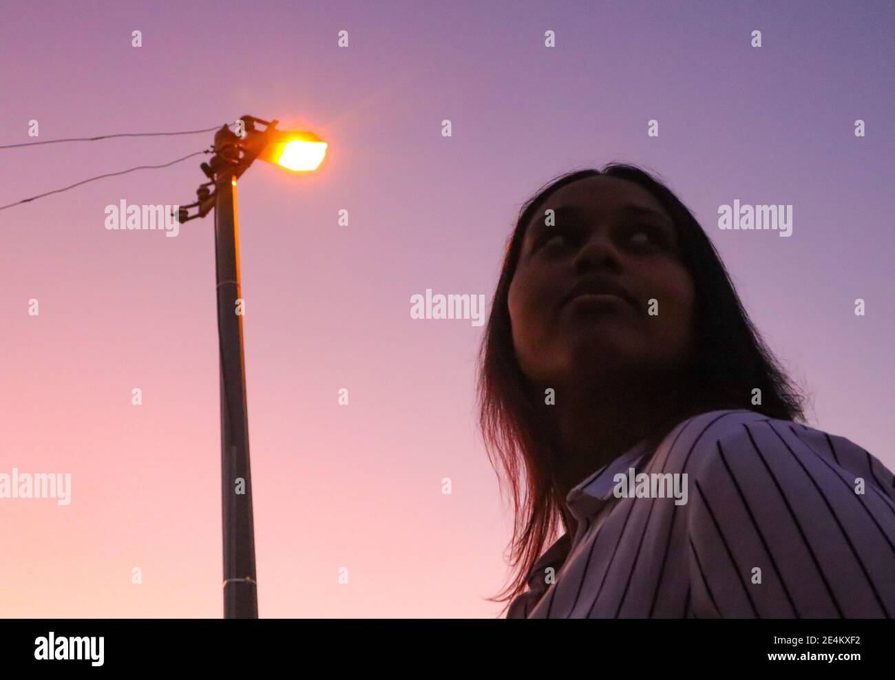 Kapstadt, Südafrika - 20-02-2020 Kreative und dunstig lila Sonnenuntergang und Straßenlaterne. Stilvolle junge Frau Silhouetten im Vordergrund. Stockfoto