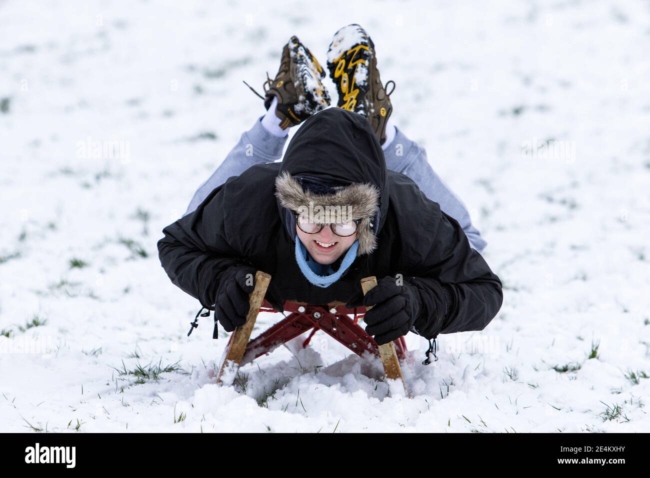 Chippenham, Wiltshire, Großbritannien. Januar 2021. Während die Chippenham-Bewohner zu ihrem ersten Schnee des Jahres aufwachen, wird ein Junge, der den Schnee genießt, bevor er auftaut, in einem lokalen Park in Chippenham abgebildet, während er auf einem Schlitten einen Hügel hinunterfährt. Quelle: Lynchpics/Alamy Live News Stockfoto